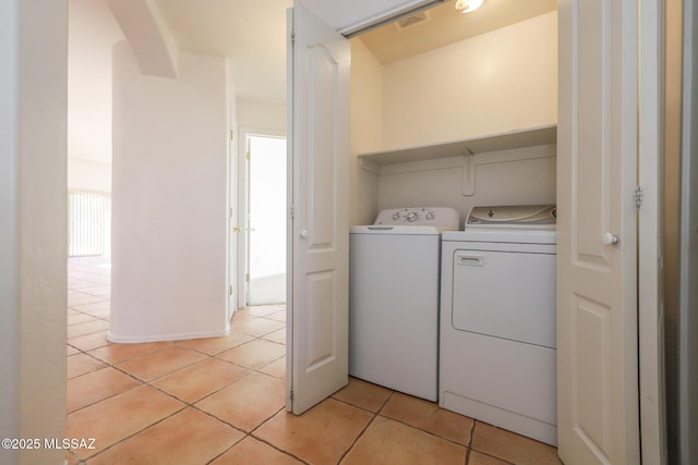 clothes washing area with separate washer and dryer and light tile patterned floors