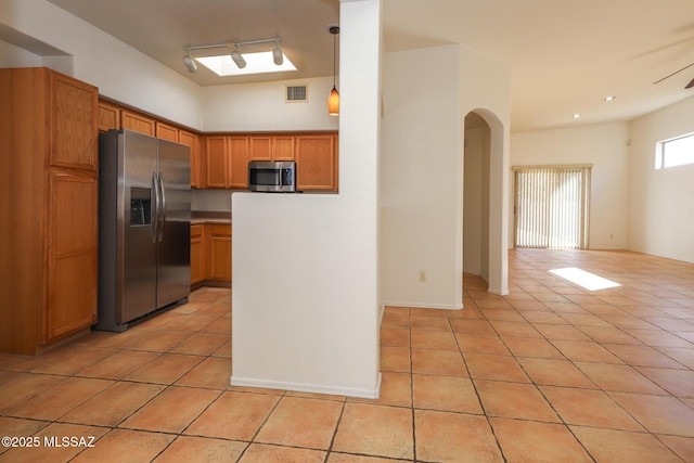 kitchen featuring appliances with stainless steel finishes, light tile patterned floors, track lighting, and decorative light fixtures