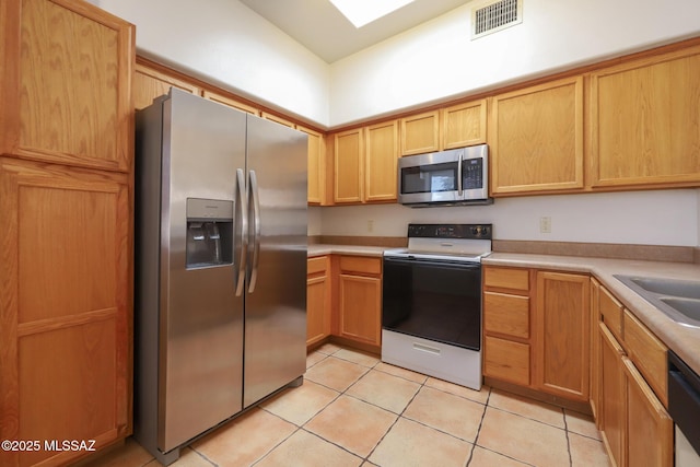 kitchen with stainless steel appliances, a skylight, and light tile patterned floors