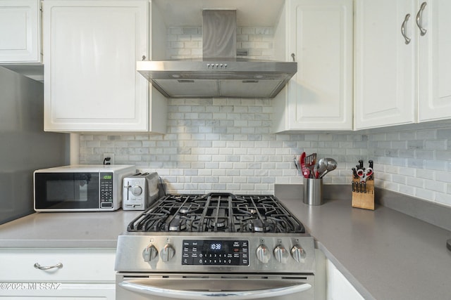 kitchen featuring tasteful backsplash, white cabinetry, stainless steel range with gas stovetop, and wall chimney range hood