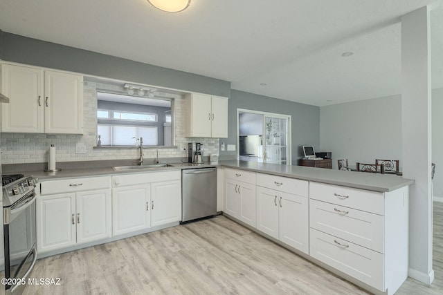 kitchen with sink, white cabinets, light hardwood / wood-style floors, kitchen peninsula, and stainless steel appliances