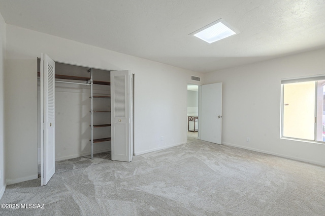 unfurnished bedroom with light colored carpet and a closet