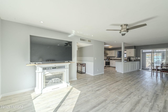 unfurnished living room with ceiling fan and light wood-type flooring