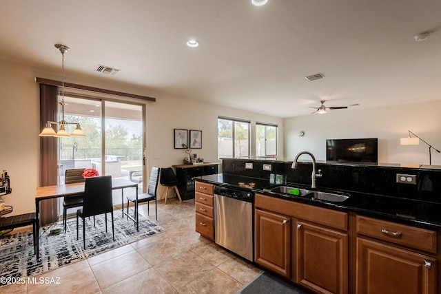 kitchen with decorative light fixtures, sink, dark stone counters, stainless steel dishwasher, and ceiling fan