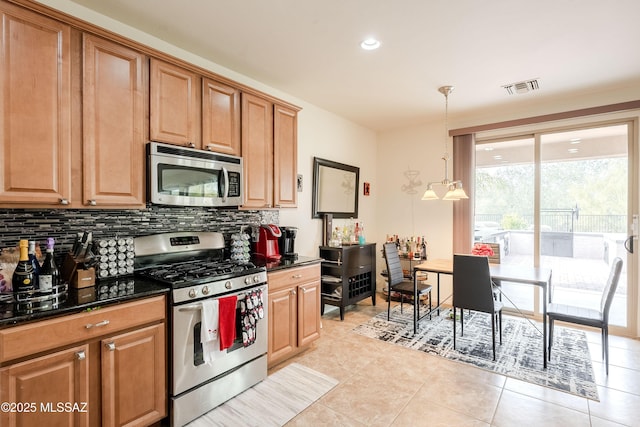 kitchen with light tile patterned floors, dark stone countertops, pendant lighting, stainless steel appliances, and decorative backsplash