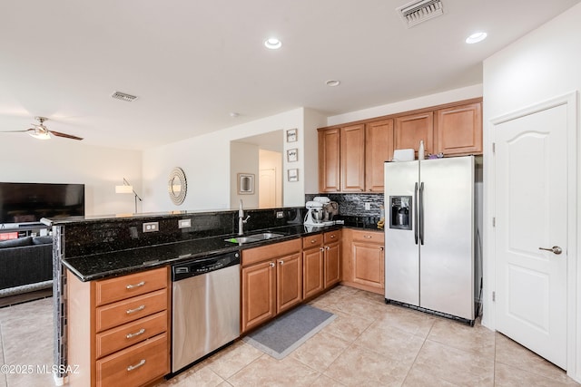 kitchen with appliances with stainless steel finishes, tasteful backsplash, sink, dark stone counters, and kitchen peninsula