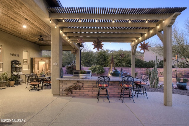 patio terrace at dusk featuring exterior bar and a pergola