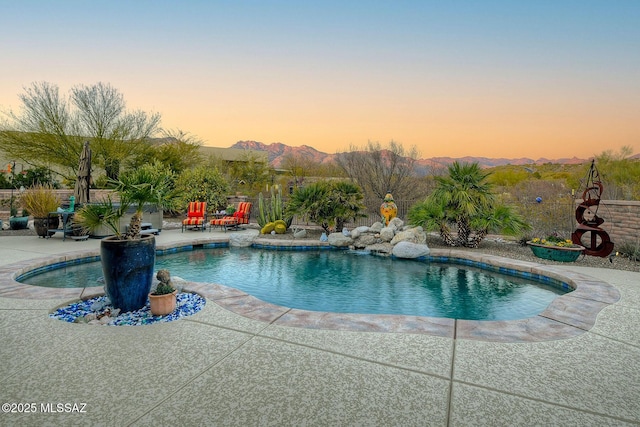 pool at dusk with a mountain view and a patio area