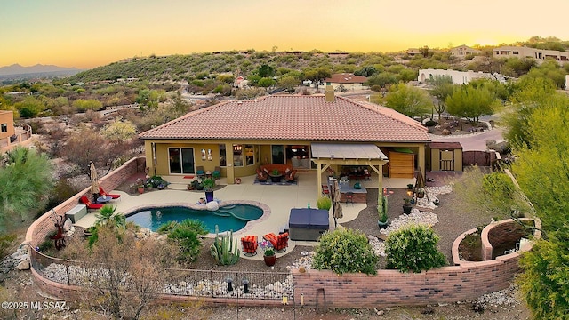 pool at dusk with a patio area