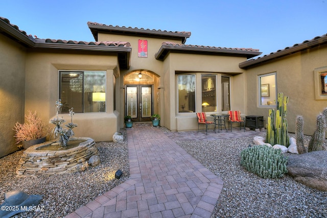 exterior entry at dusk featuring a patio and french doors