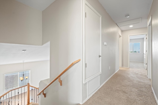 corridor featuring light carpet, lofted ceiling, and an inviting chandelier