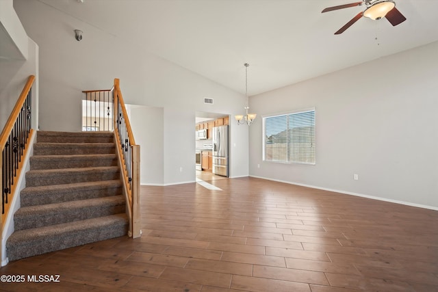 unfurnished living room with dark hardwood / wood-style floors, ceiling fan with notable chandelier, and high vaulted ceiling