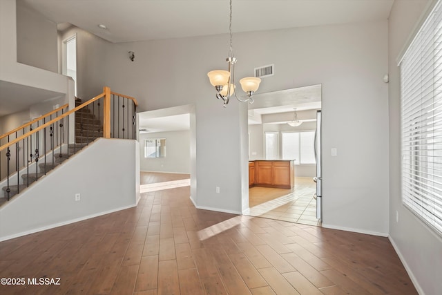 unfurnished dining area with high vaulted ceiling, hardwood / wood-style floors, and an inviting chandelier