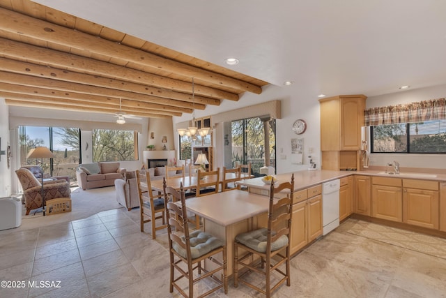 dining space with beamed ceiling, plenty of natural light, an inviting chandelier, and sink