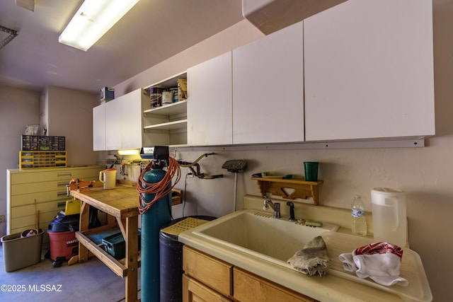 kitchen featuring white cabinetry, concrete flooring, and sink