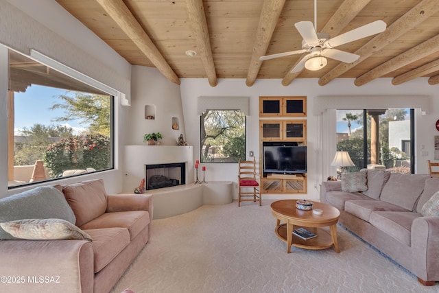 living room featuring beamed ceiling, a large fireplace, ceiling fan, and wooden ceiling