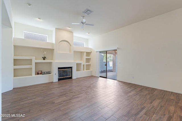 unfurnished living room featuring a high ceiling, ceiling fan, and built in shelves