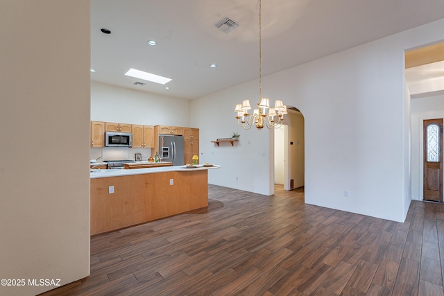 kitchen featuring dark hardwood / wood-style floors, appliances with stainless steel finishes, decorative light fixtures, and kitchen peninsula