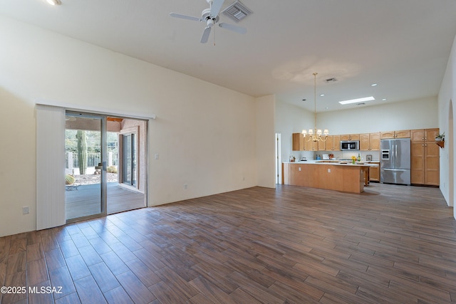 unfurnished living room with a towering ceiling and ceiling fan with notable chandelier