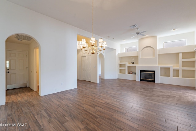 unfurnished living room with dark wood-type flooring, ceiling fan with notable chandelier, and built in shelves