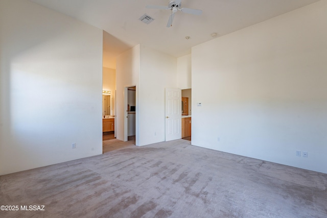 spare room with a towering ceiling, light carpet, and ceiling fan