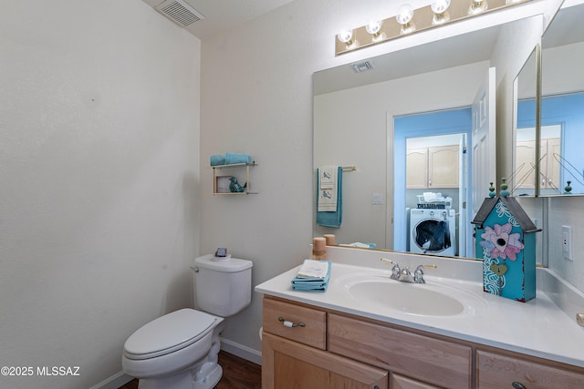 bathroom featuring vanity, washer / dryer, and toilet