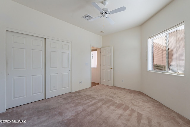 unfurnished bedroom with light carpet, a closet, and ceiling fan