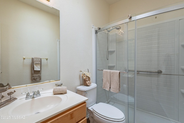 bathroom featuring vanity, a shower with door, and toilet