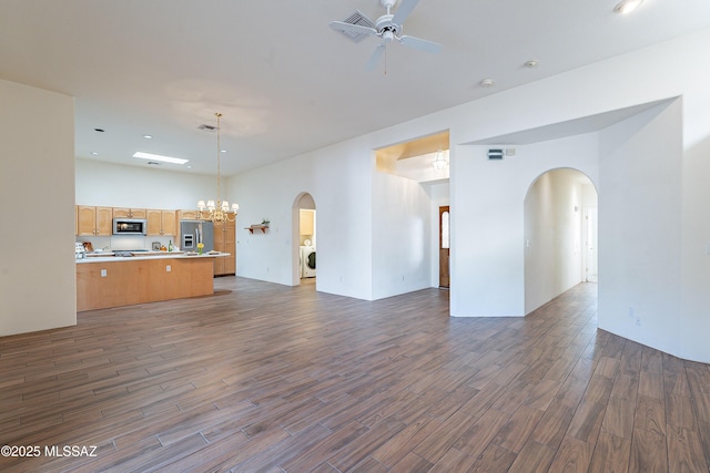 unfurnished living room featuring washer / clothes dryer, ceiling fan with notable chandelier, and a towering ceiling