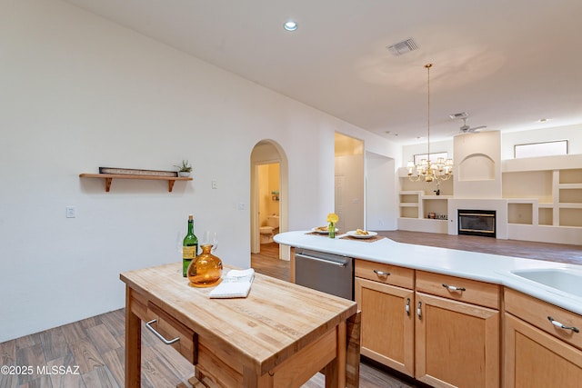 kitchen with pendant lighting, dark wood-type flooring, dishwasher, a kitchen island, and ceiling fan with notable chandelier