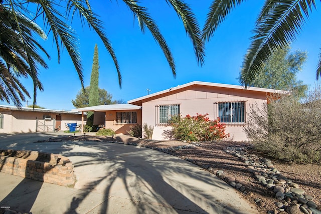 ranch-style house with stucco siding and a gate