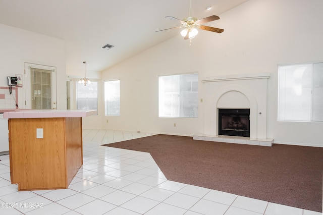 kitchen featuring pendant lighting, a fireplace, tile counters, and light tile patterned flooring