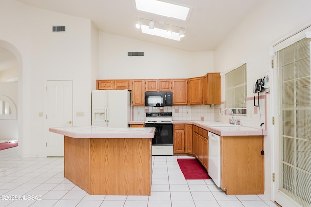 kitchen with sink, white appliances, tile countertops, and a center island