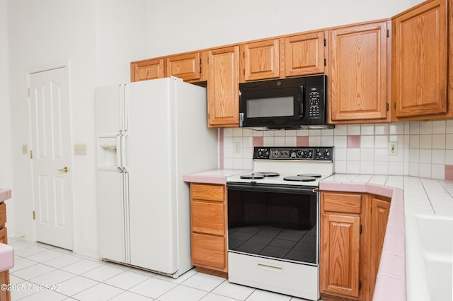 kitchen featuring tasteful backsplash, light tile patterned flooring, tile counters, and white appliances