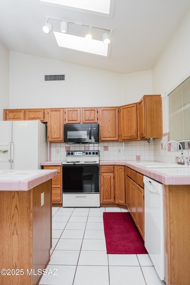 kitchen featuring light tile patterned flooring, sink, tile countertops, and white appliances