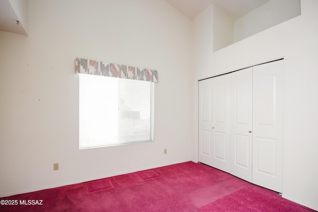 unfurnished bedroom with a towering ceiling, carpet floors, and a closet