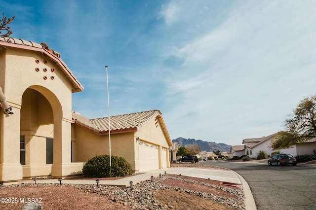 1524 W Sunridge Dr, Tucson, AZ 85704 - view of property exterior featuring a mountain view, a tiled roof, a garage, stucco siding, and driveway