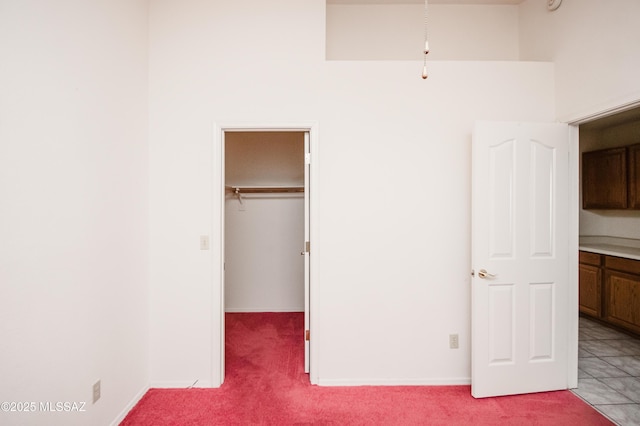 unfurnished bedroom featuring light colored carpet, a spacious closet, and a closet