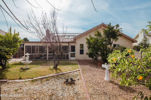 back of property with a sunroom and a lawn