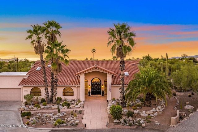 view of front of house with stucco siding, driveway, and a tiled roof