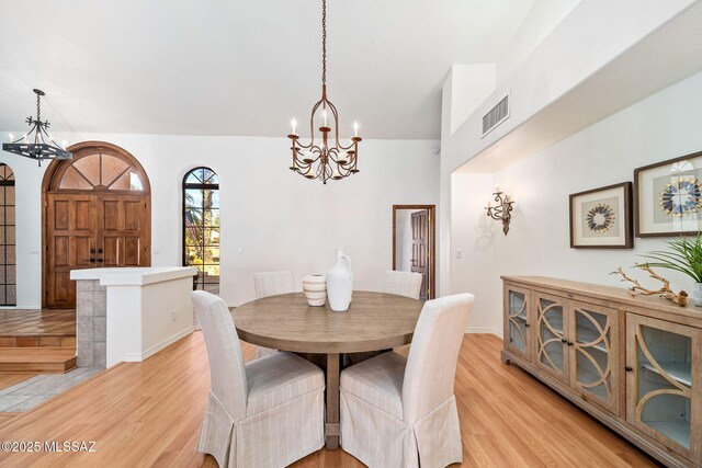 dining room featuring a high ceiling, a notable chandelier, and light hardwood / wood-style flooring