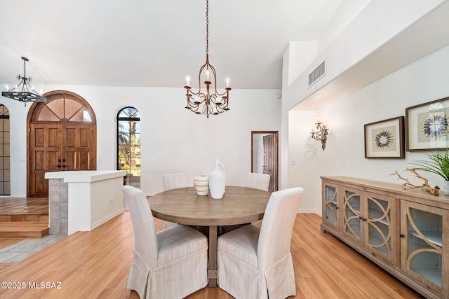 dining area featuring a notable chandelier, light wood-style flooring, and visible vents