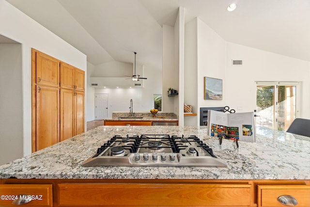 kitchen with visible vents, stainless steel gas cooktop, vaulted ceiling, brown cabinets, and a sink