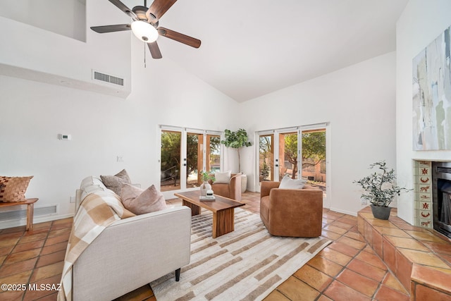 living area featuring visible vents, baseboards, high vaulted ceiling, and a tile fireplace