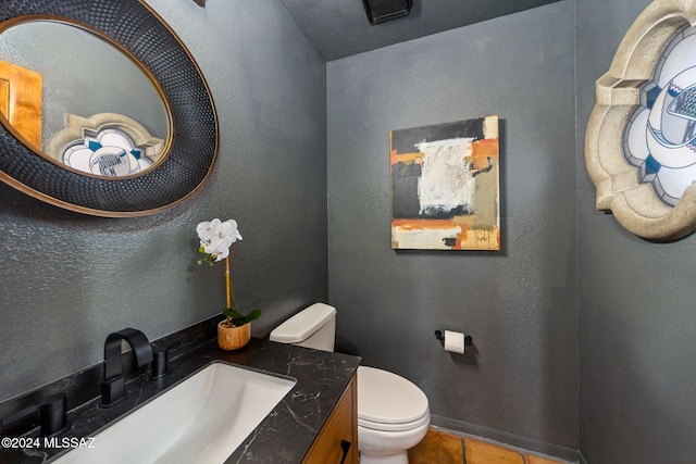 bathroom featuring tile patterned floors, toilet, vanity, and a textured wall