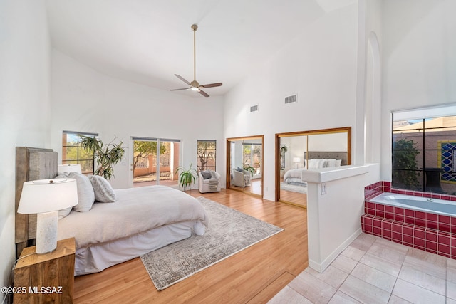 bedroom featuring a towering ceiling, a ceiling fan, visible vents, and light wood finished floors