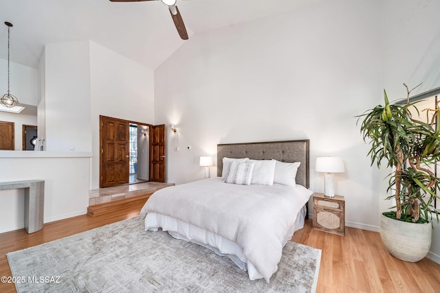 bedroom featuring ceiling fan, high vaulted ceiling, baseboards, and wood finished floors