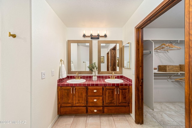 bathroom with double vanity, a walk in closet, and a sink