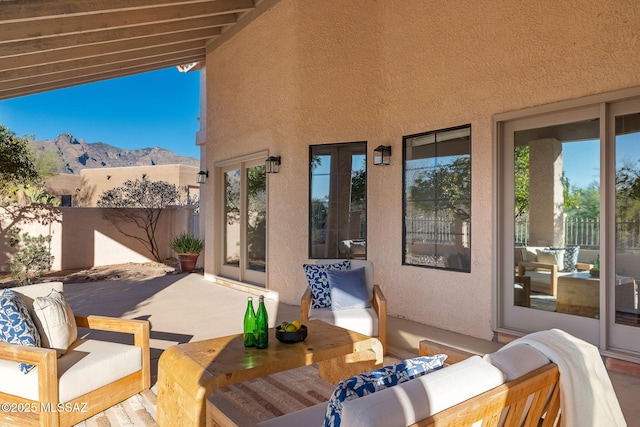 view of patio featuring an outdoor living space, a mountain view, and fence