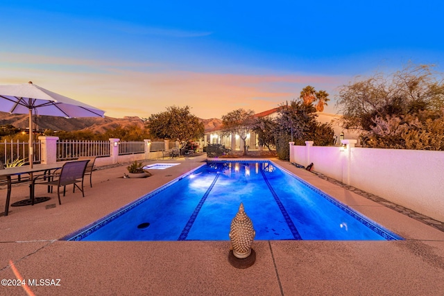 pool at dusk featuring a patio